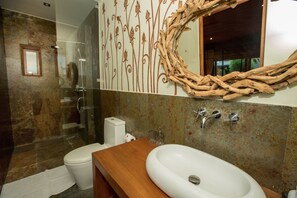 A bathroom with a wooden vanity, a white sink, and a glass shower enclosure.