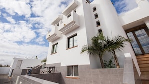 Un edificio moderno con techo plano, varias ventanas y una escalera que conduce a un nivel superior.