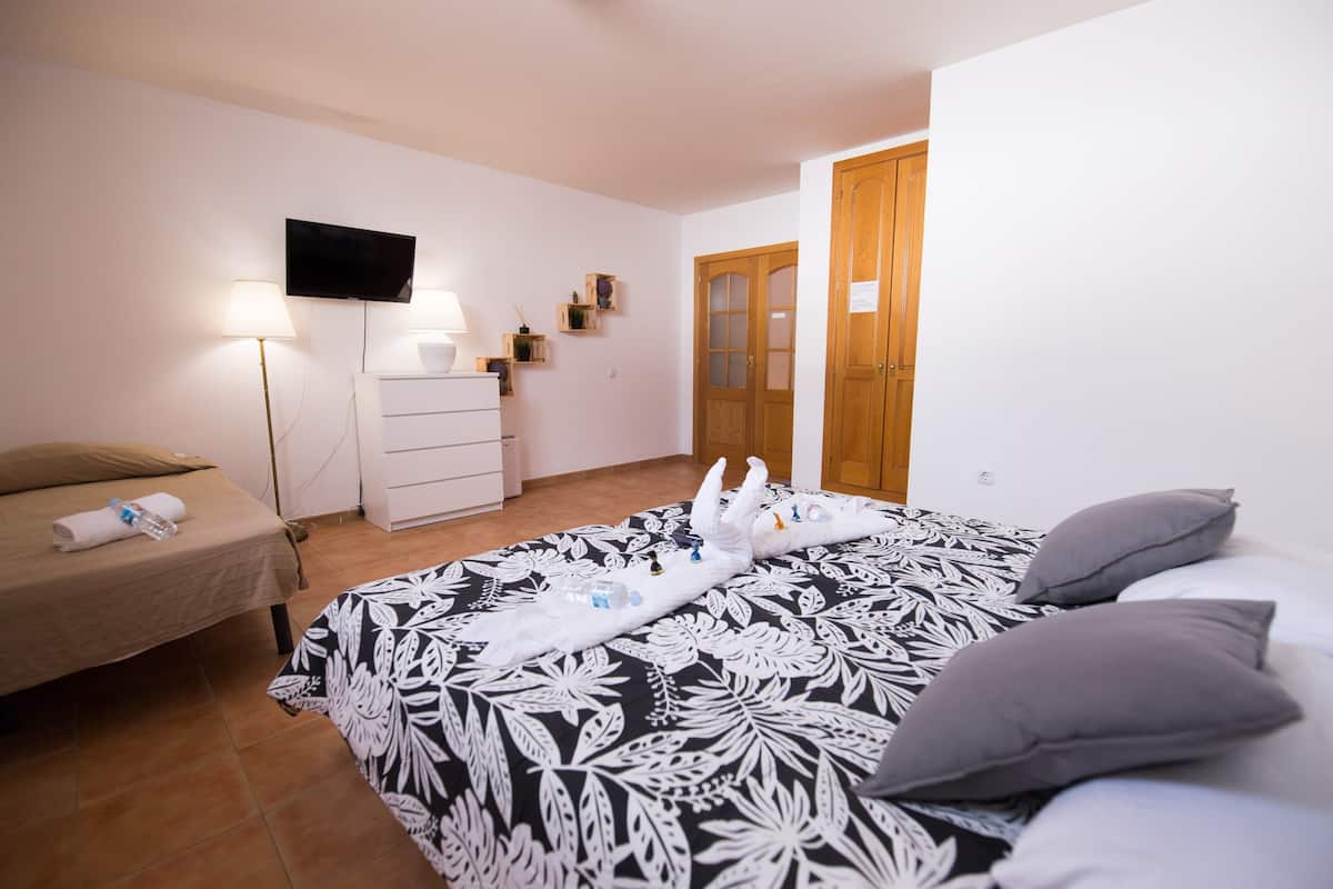 A hotel room with a bed, a TV, a dresser, and a wooden door.