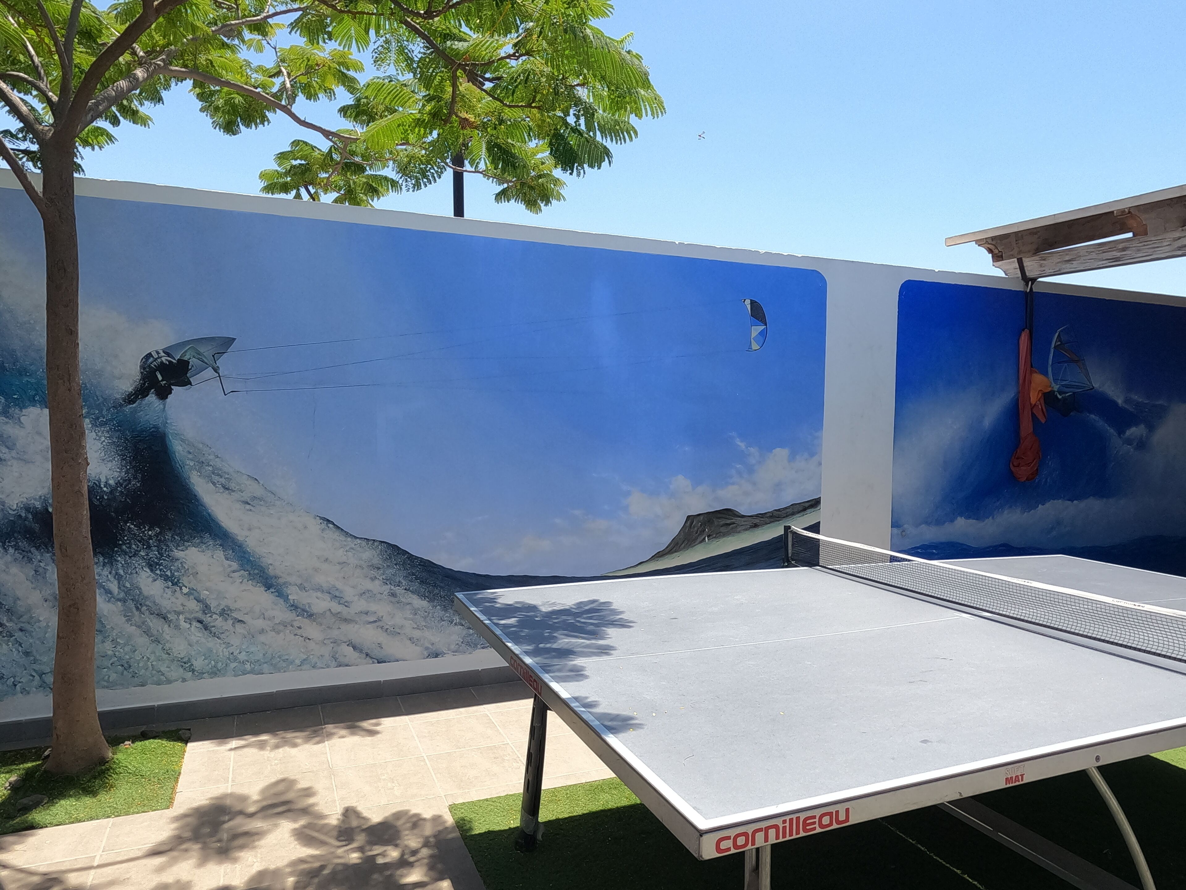 A ping pong table with a mural of a surfer riding a wave.