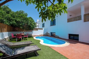 A backyard with a swimming pool, a wooden deck, and a patio area.