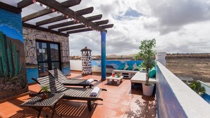 Una terraza con dos sillones, una mesita y una planta en maceta.