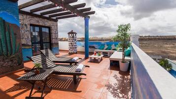 Relax on the rooftop terrace with lounge chairs, a small table, and a potted plant, taking in the breathtaking views.