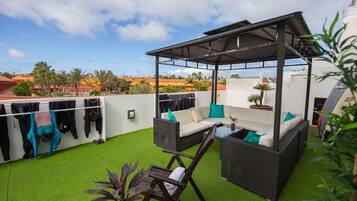 An outdoor patio with a covered seating area, artificial grass, and a row of hanging clothes.