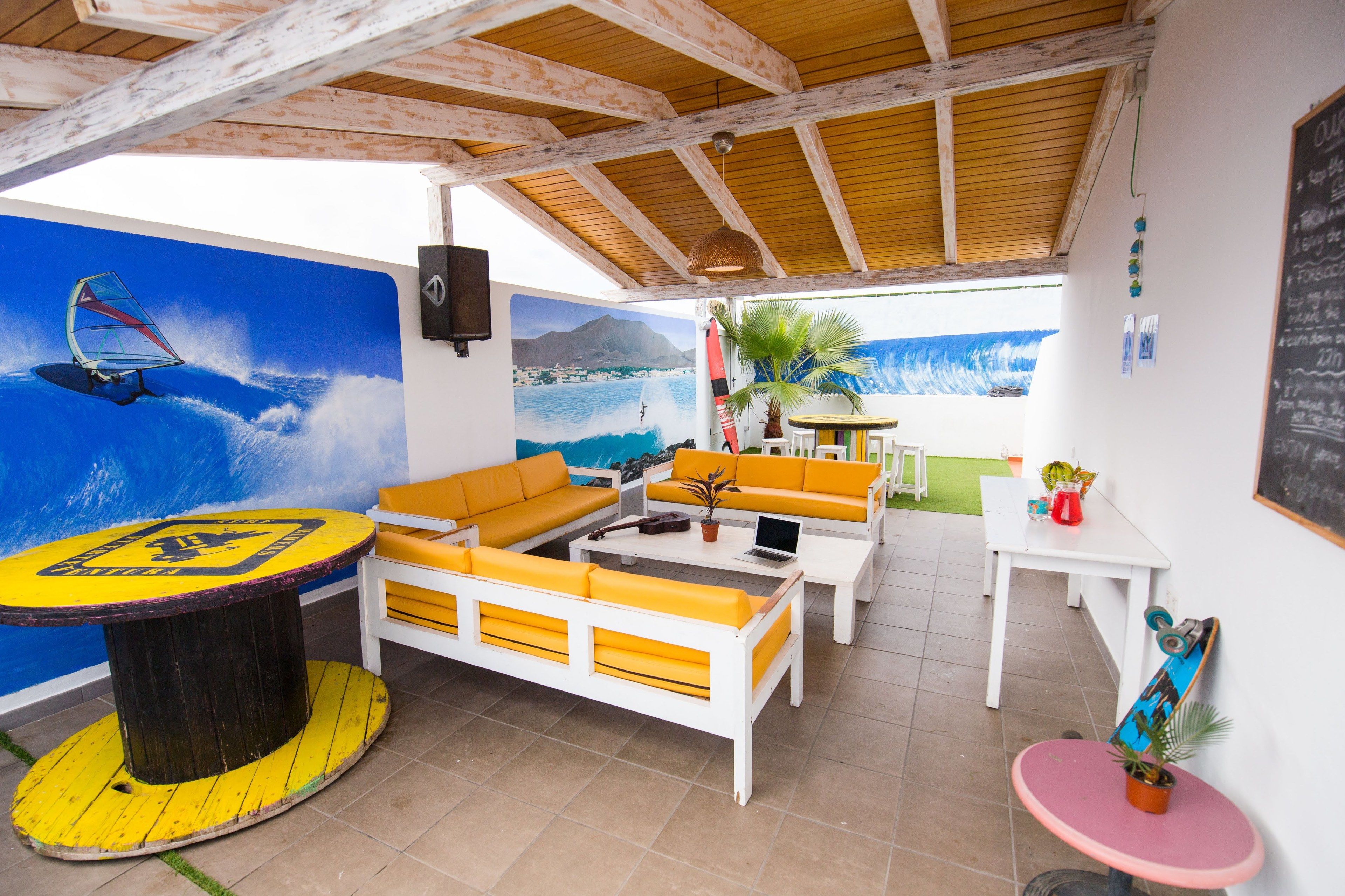 A beach-themed room with a mural, yellow and white furniture, a round table, and a skateboard.