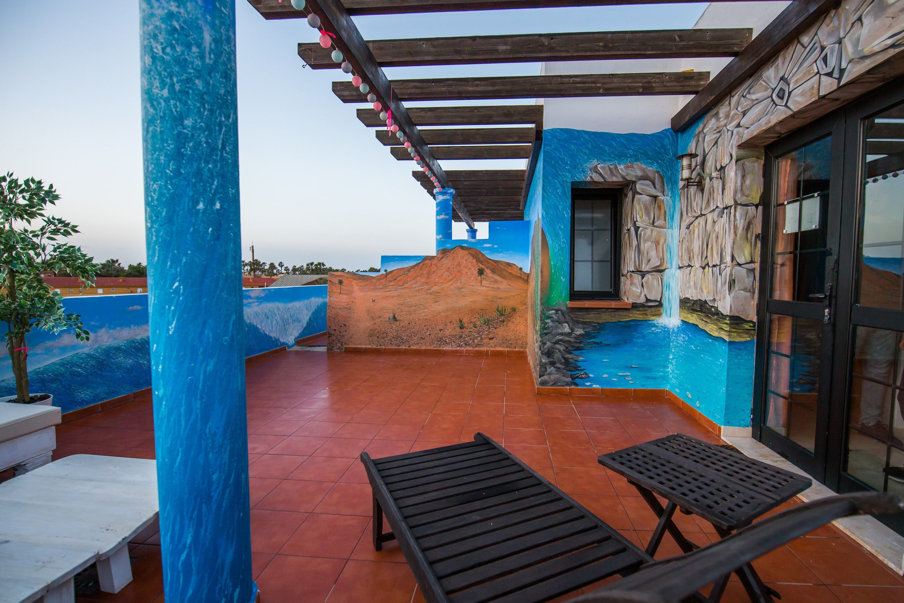 A rooftop patio with a pool, wooden pergola, and stone wall.