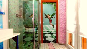 Un pasillo estrecho con suelo a cuadros, un recinto de vidrio con aves y una puerta decorada con un mural fantasioso.
