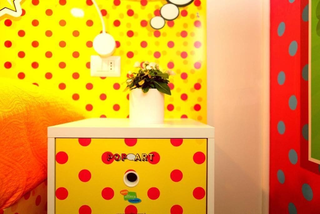 Une pièce aux couleurs vives, avec un mur jaune à pois et un meuble blanc orné de pois rouges.