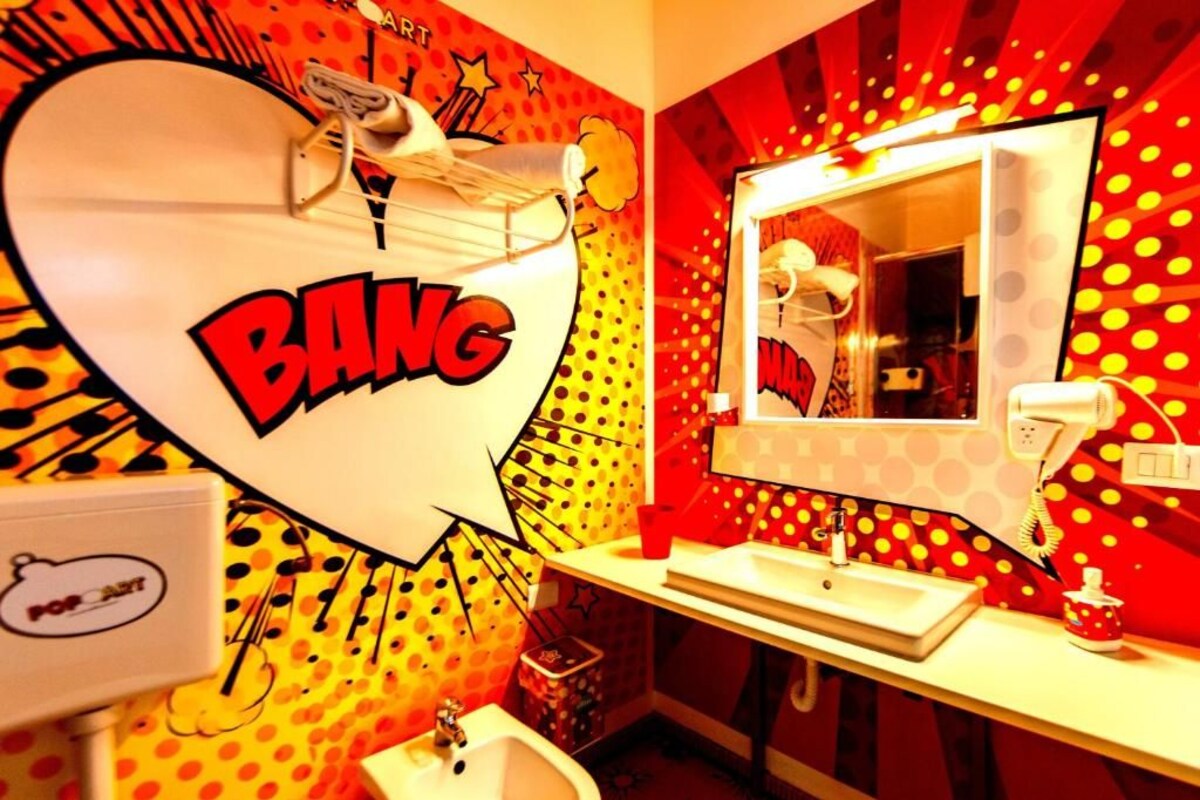 A bathroom with a vibrant, comic-style mural, a sink, and a mirror.