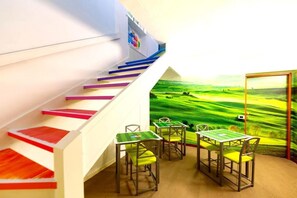 A children's playroom with a colorful staircase, a green landscape mural, and a small table with chairs. - Pavia AffittaCamere (Pavia)