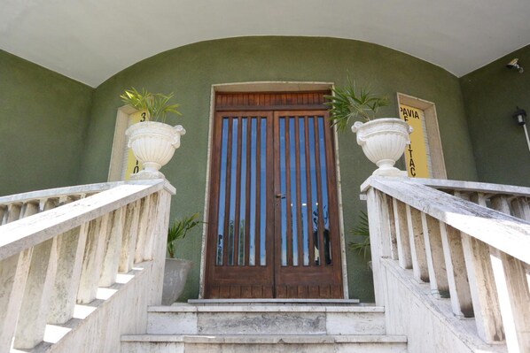 Una escalera con una puerta de madera y dos grandes jarrones blancos a cada lado.