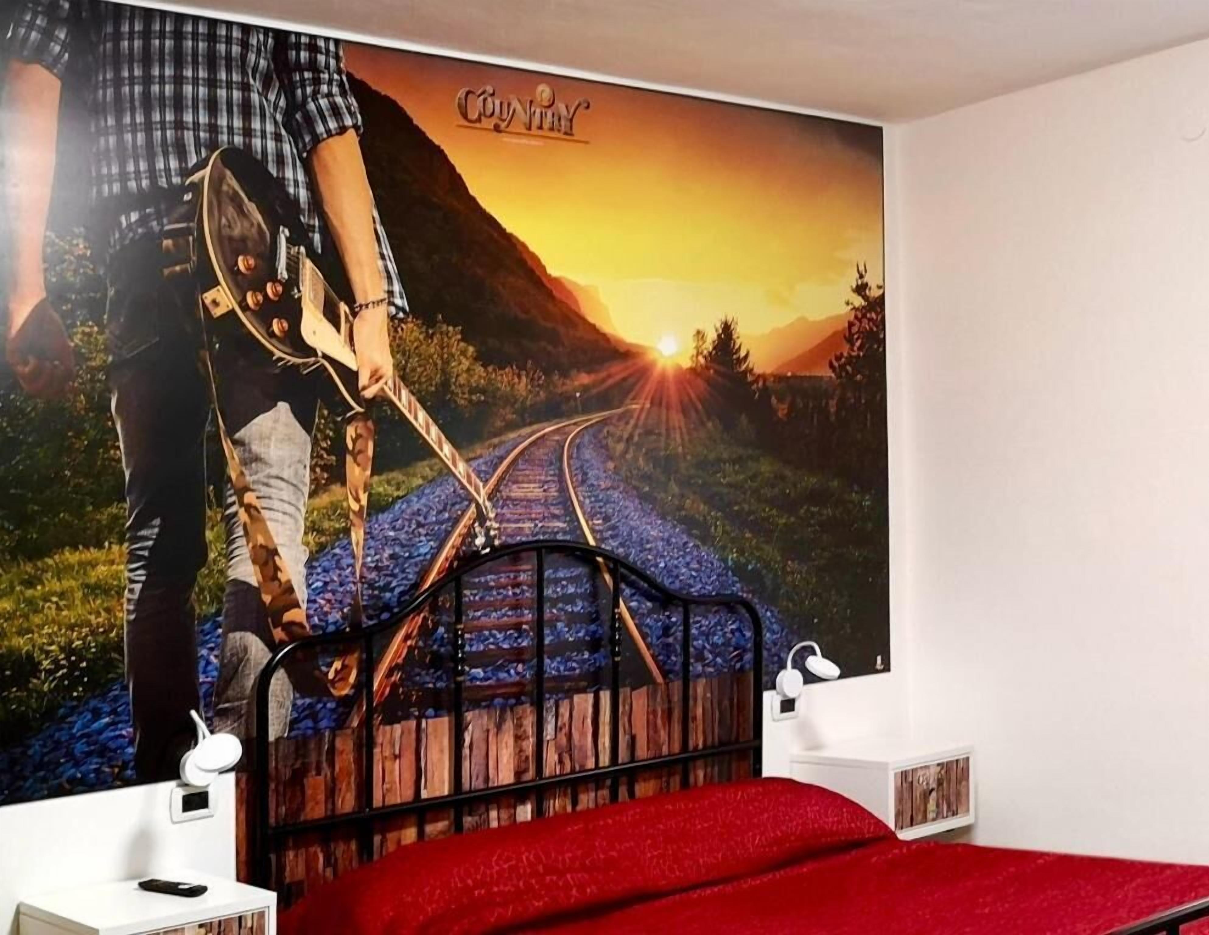 A bedroom with a bed, a nightstand, and a wall-mounted shelf.