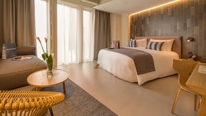 Ein modernes Hotelzimmer mit einem großen Bett, einer Couch, einem kleinen runden Tisch und einem Sessel.