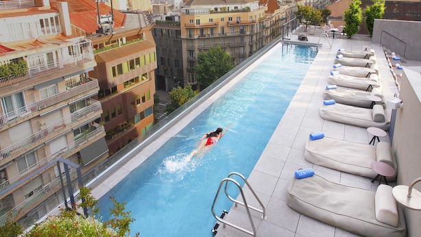 Ein Dachpool mit Blick auf die Stadt, Liegestühle und ein Sprungbrett.