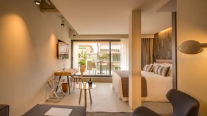 Ein modernes Hotelzimmer mit Bett, Schreibtisch, Stuhl und einem Balkon mit Blick auf die Stadt.