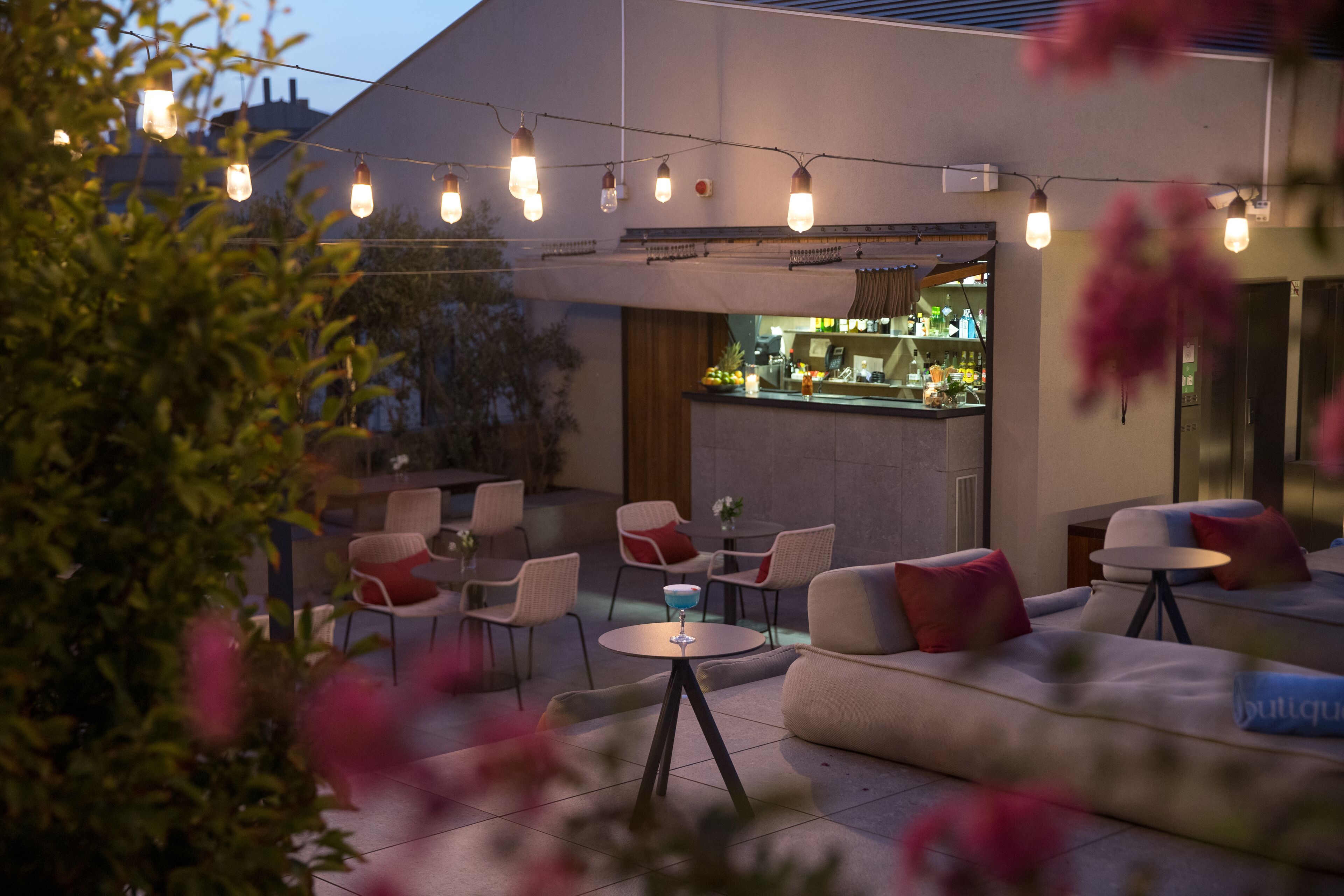 Un espacio al aire libre con barra, sillas acolchadas y un sofá.