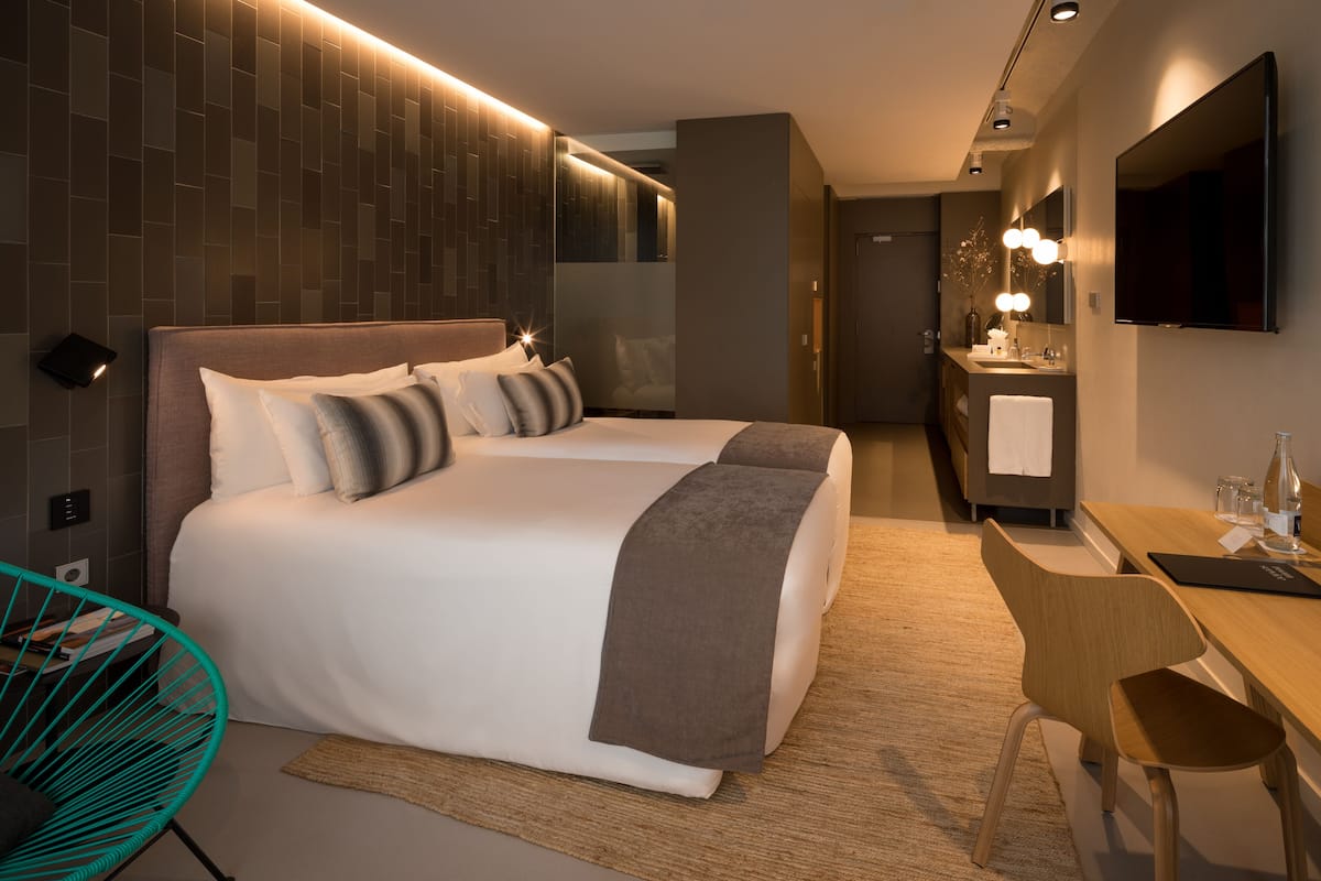 A modern hotel room with a large bed, a desk, a chair, a bathroom, and a TV.