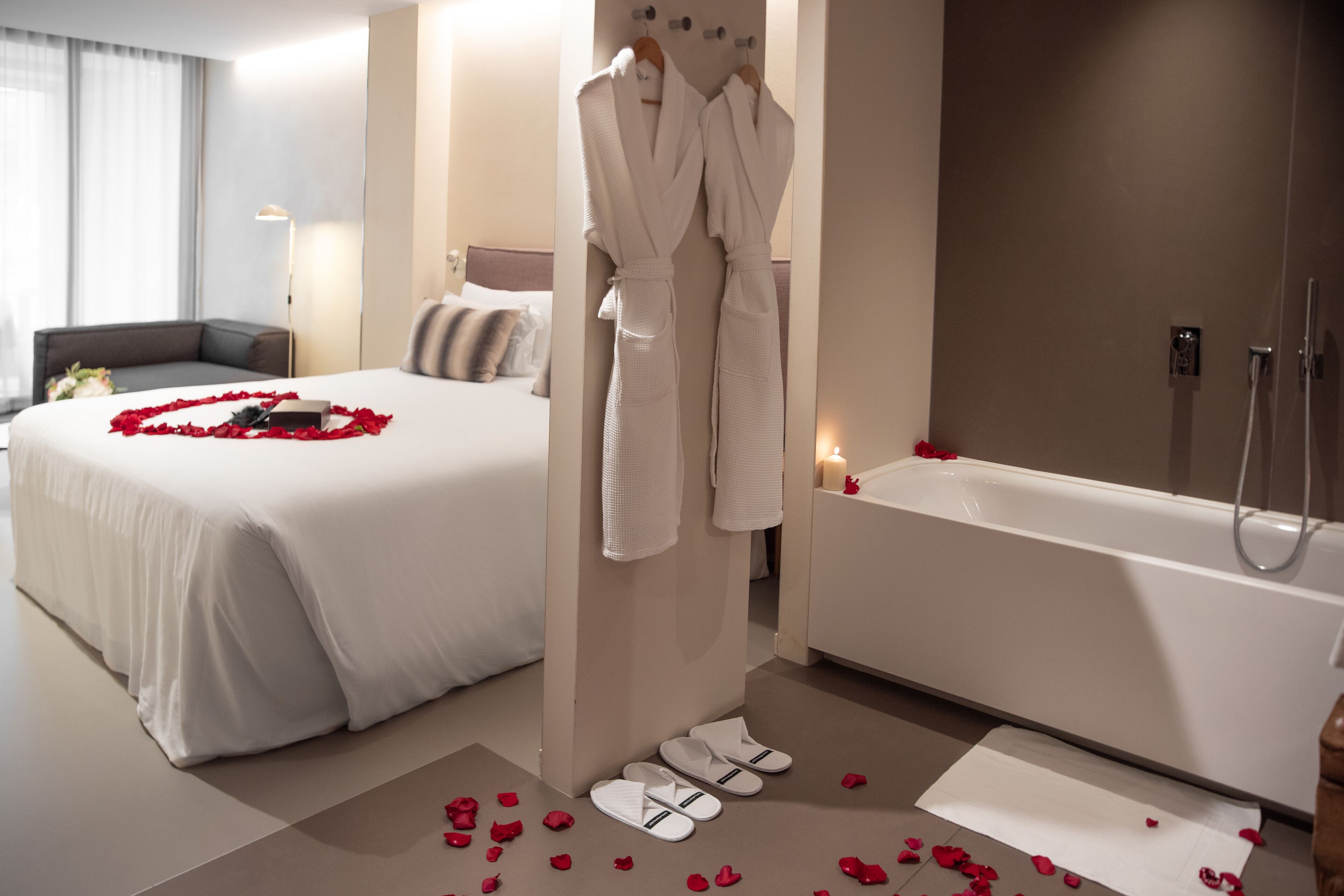 Habitación de hotel con una cama grande, una bañera y un perchero para bata.