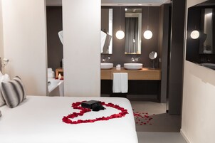 Una camera d'albergo con un letto, un bagno con uno specchio e un lavandino.