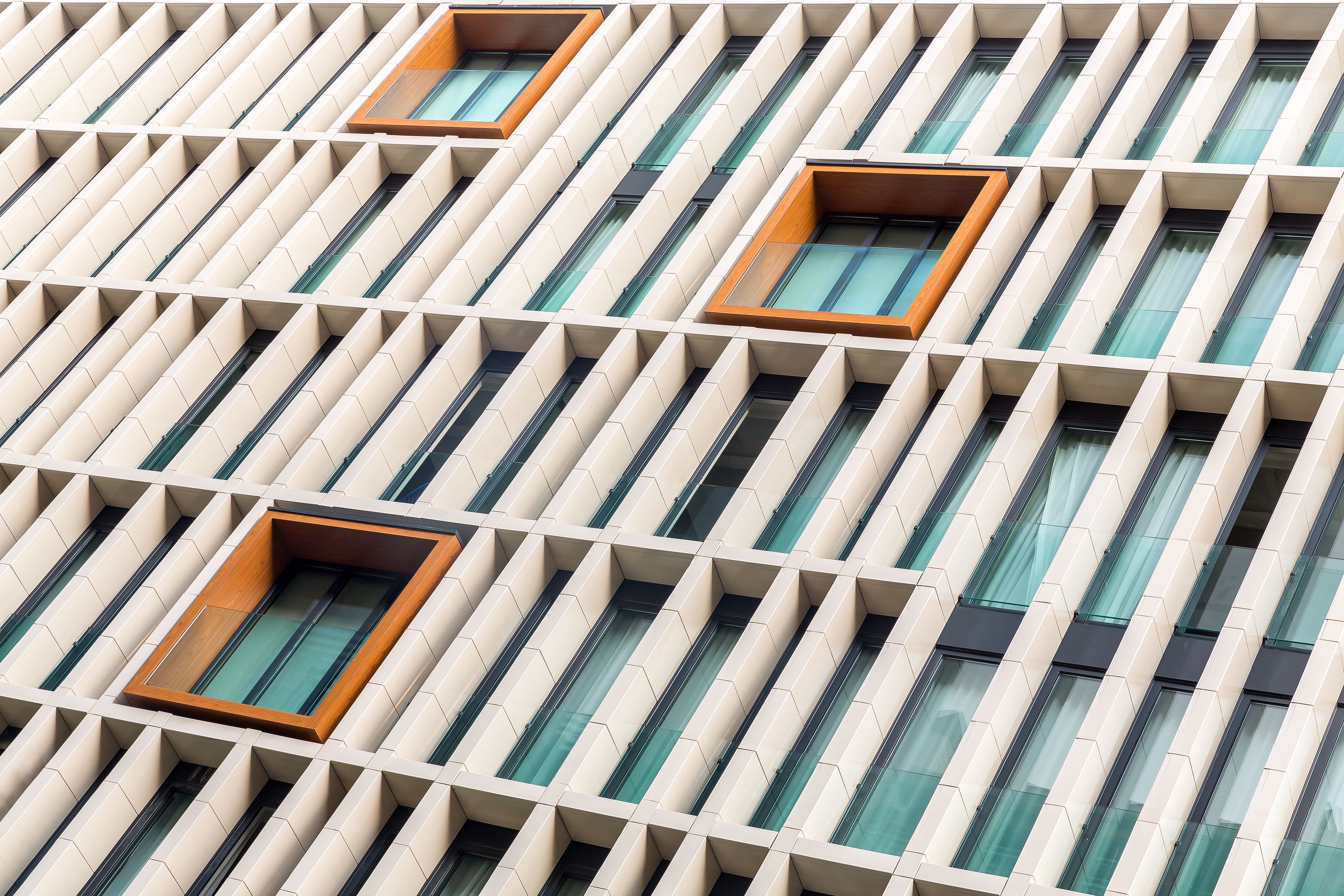 Fachada de edificio con un patrón geométrico repetido de ventanas y balcones.