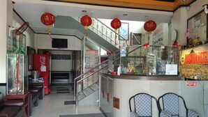 A hotel lobby with a reception desk, seating area, staircase, and decorative elements like red lanterns. - Magayon Hotel (Legazpi)