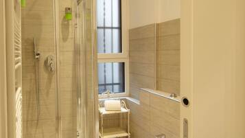 A modern bathroom with a glass-enclosed shower, a freestanding bathtub, and a toilet.