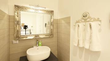 A bathroom with a large ornate mirror, a white sink, and a towel rack with white towels.