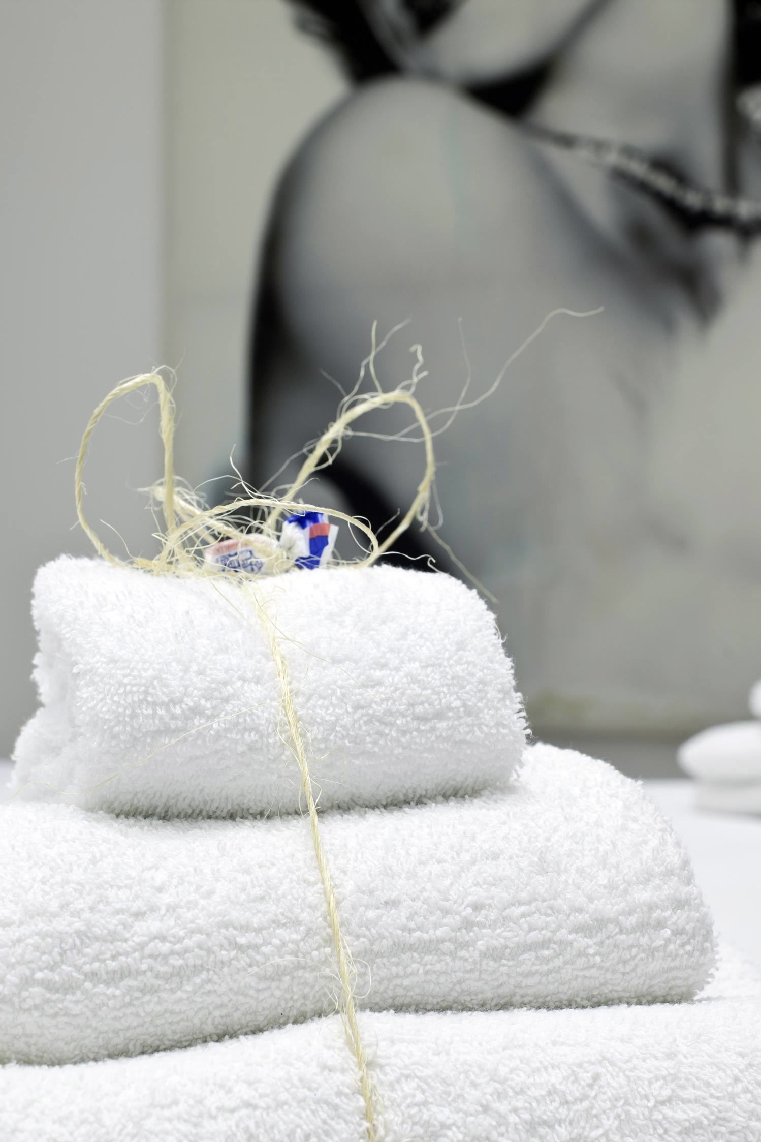 Une pile de serviettes blanches, avec une ficelle et un petit objet bleu posé dessus.