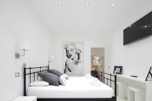 A modern bedroom with a bed, a painting, a TV, and a bathroom visible in the background. - Affittacamere Arosio (Monza)