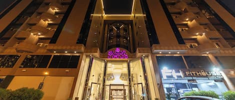 A modern building with a prominent entrance, large glass windows, and a well-lit facade.