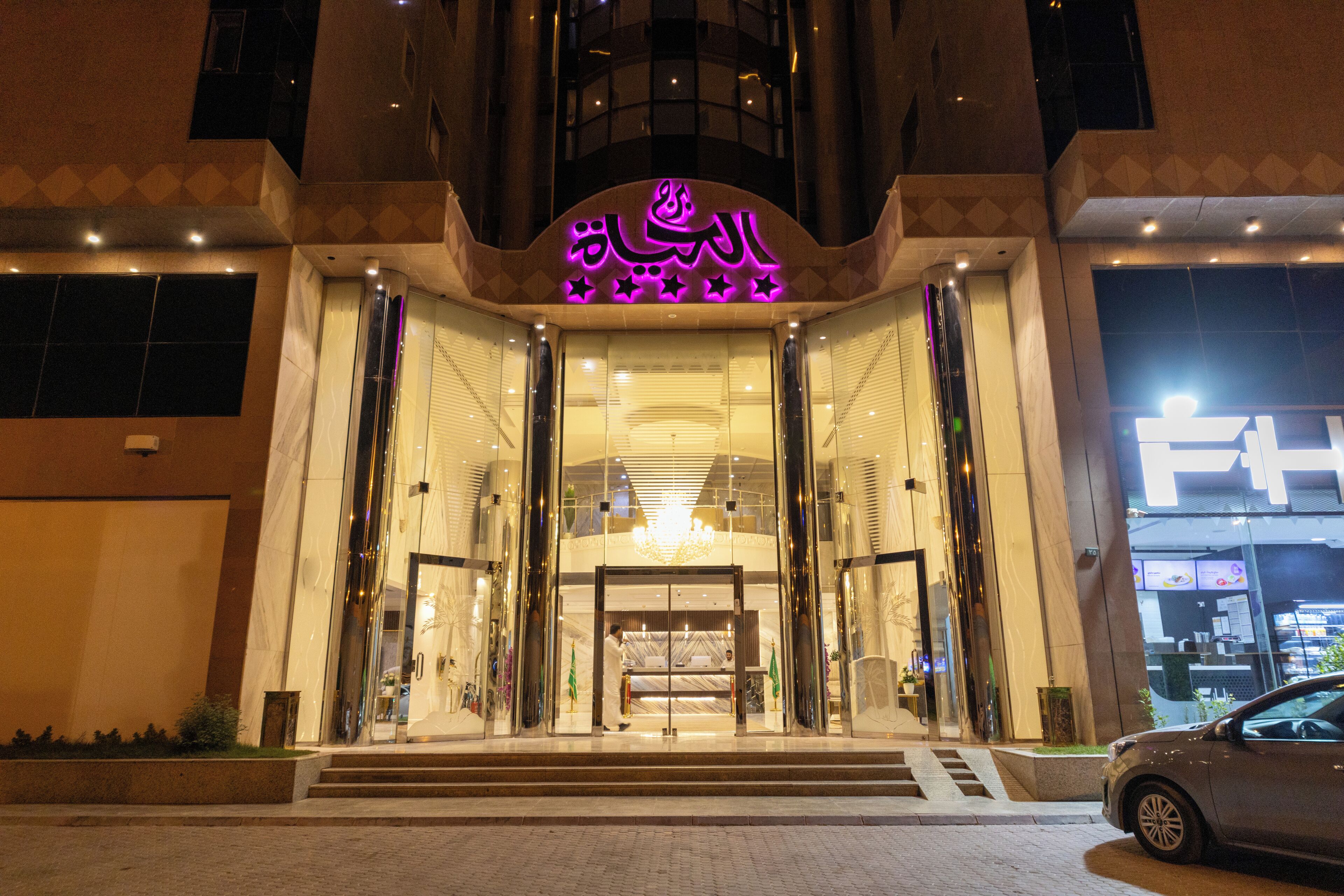 A hotel entrance with a prominent sign, glass doors, and a staircase leading up to the entrance.