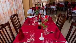 Mesa de comedor vestida con mantel rojo, caminos de mesa blancos y servilletas rojas.