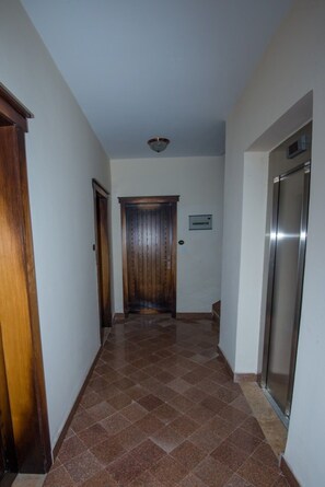 A hallway with a wooden door, a metal elevator, and a wall-mounted intercom. - Wudasie Castle Hotel (Addis Ababa)