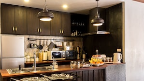 A modern kitchen with dark wooden cabinets, stainless steel appliances, and pendant lighting. - ONCE (upon a time) Chiang Mai Boutique Home (Chiang Mai)