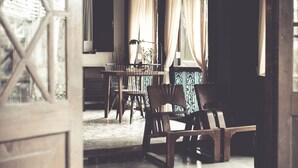 An interior view of a room with a wooden table and chairs, a window with curtains, and a patterned floor. - ONCE (upon a time) Chiang Mai Boutique Home (Chiang Mai)