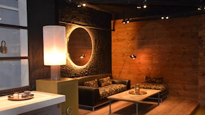Een knus ingerichte kamer met een ronde spiegel, een bank, een salontafel en een lamp.
