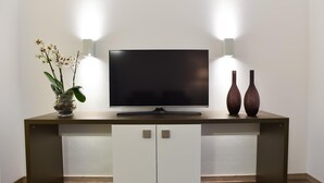A modern entertainment unit with a flat-screen TV, two wall-mounted lights, and two decorative vases. - Guesthouse Lichtenau (Nussloch)