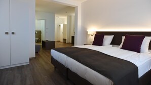 A modern hotel room with a large bed, a bedside table, a wardrobe, and a bathroom visible through an open door. - Guesthouse Lichtenau (Nussloch)