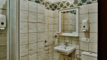 Un baño con ducha, lavamanos, inodoro y espejo.