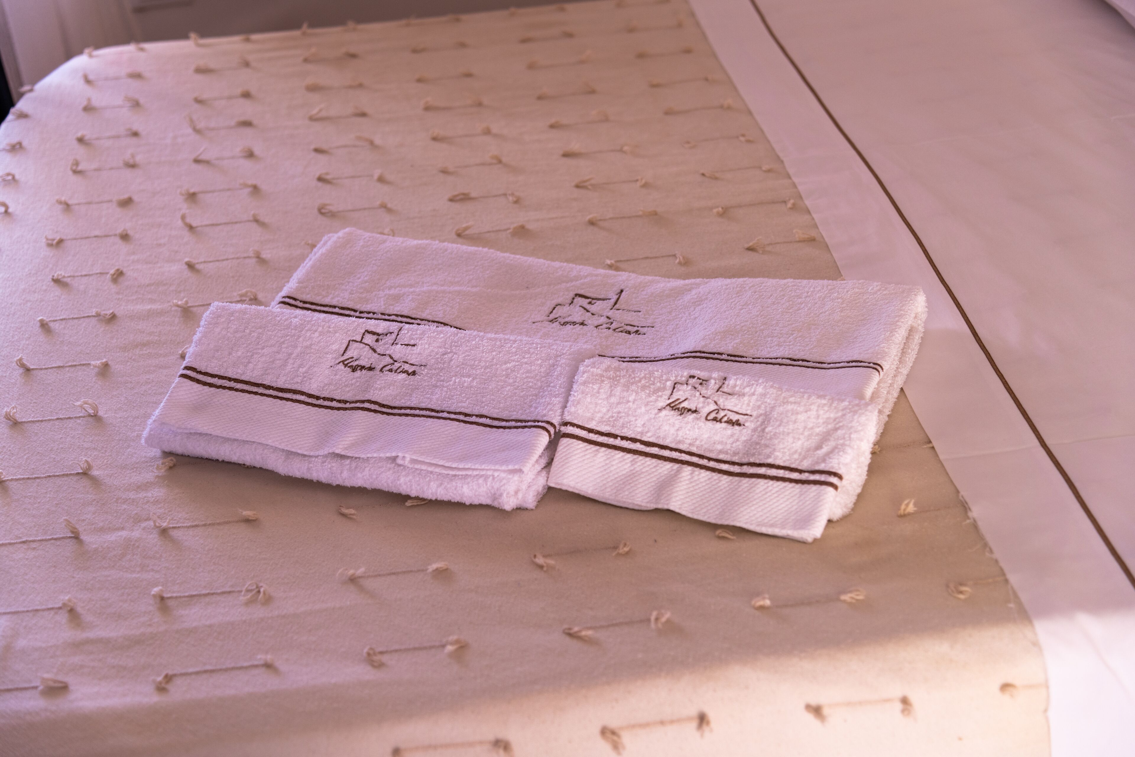 A neatly folded towel with embroidered text on a bed with a textured surface.