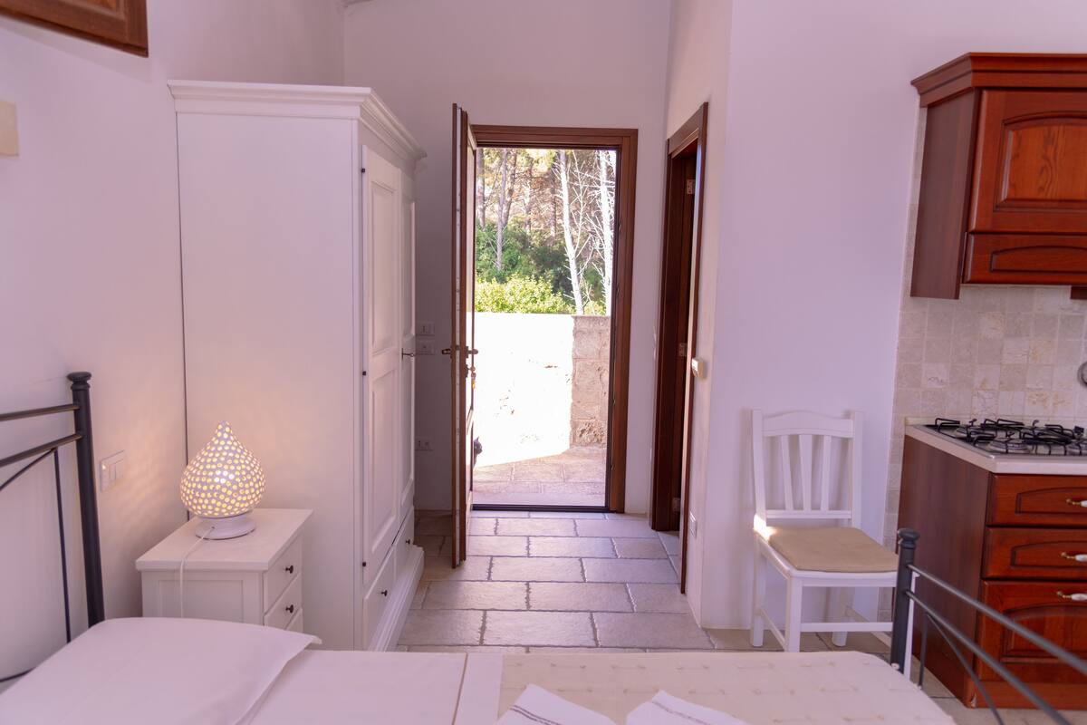 A bedroom with a bed, a bedside lamp, a nightstand, and a wardrobe.