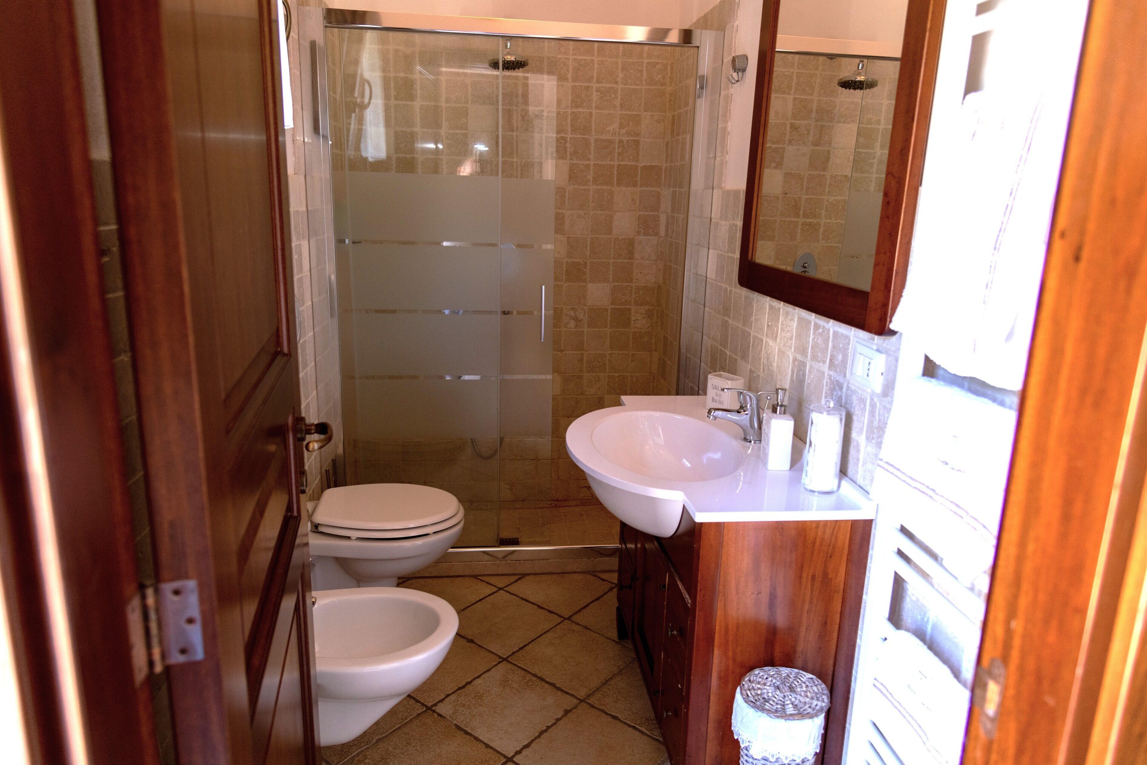 A bathroom with a toilet, bidet, and a glass-enclosed shower.