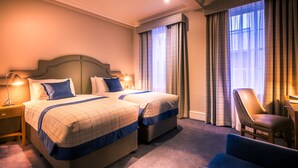 A hotel room with two beds, a chair, and a desk. - Bishop's Gate Hotel (Londonderry)