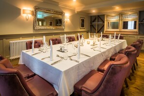 A long dining table set for a formal meal with multiple chairs, candles, and fine china. - Bishop's Gate Hotel (Londonderry)