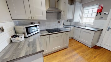 Una cocina moderna con armarios blancos, microondas integrado, estufa y ventana.