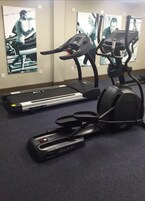 Un gimnasio con cintas de correr, elíptica y bicicleta estática.