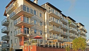A multi-story residential building with balconies, a red umbrella, and a brick facade. - IRS ROYAL APARTMENTS – IRS Morenowe Wzgórza (Gdansk)
