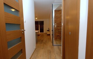 A hallway with wooden doors, a brick wall, and a window.