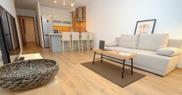 A modern living room with a sofa, a coffee table, and a kitchen area in the background.