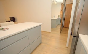 A modern kitchen with a white countertop, grey cabinets, and a wooden floor. - IRS ROYAL APARTMENTS – IRS Morenowe Wzgórza (Gdansk)